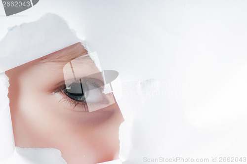 Image of Child eye looking through a hole in paper