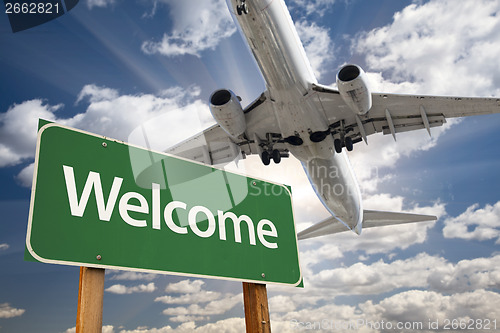 Image of Welcome Green Road Sign and Airplane Above