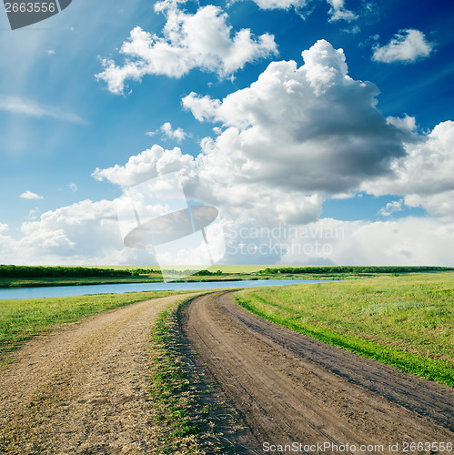 Image of rural road in green grass and cloudy sky
