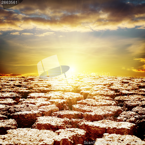 Image of cracked desert close up and sunset over it