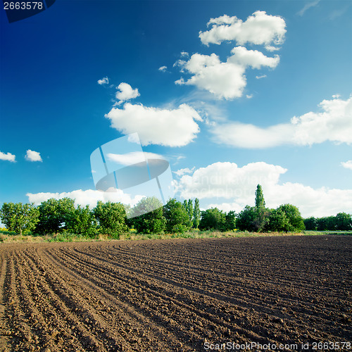 Image of black agriculture field and blue sky with clouds