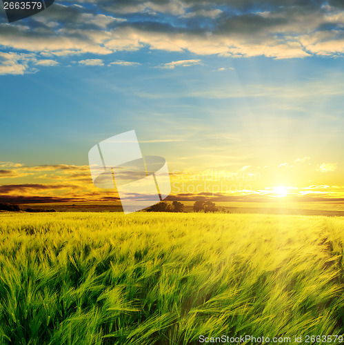Image of sunset in clouds over green field