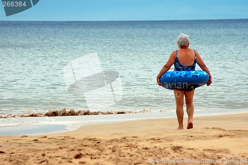 Image of an old woman to enter in the sea with a buoy