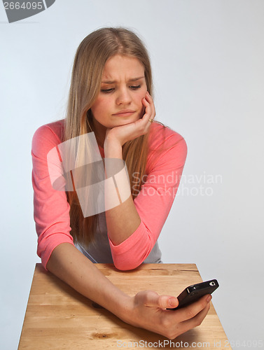 Image of Scandinavian cute young girl looking irritated at her phone