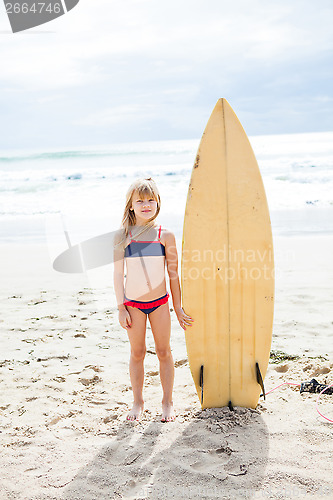 Image of Young girl standing with surfboard on beach