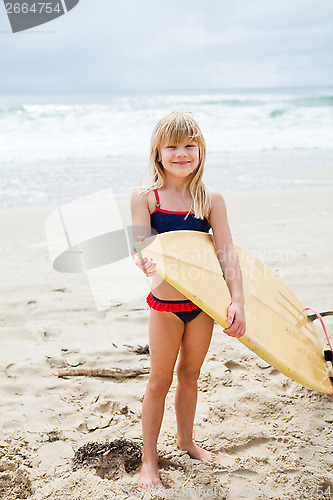 Image of Smiling young girl holding surfboard on beach