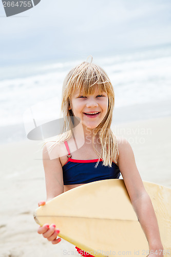 Image of Happy young girl with surfboard on beach