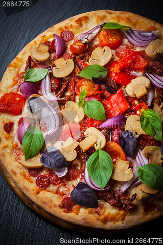 Image of Homemade pizza with dried tomatoes and salami 