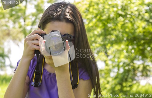Image of Young girl taking photos at summer green park