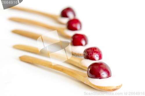 Image of Wooden spoon is with yogurt and cherries