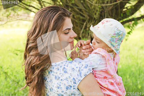 Image of Baby girl with her mother giving a flower