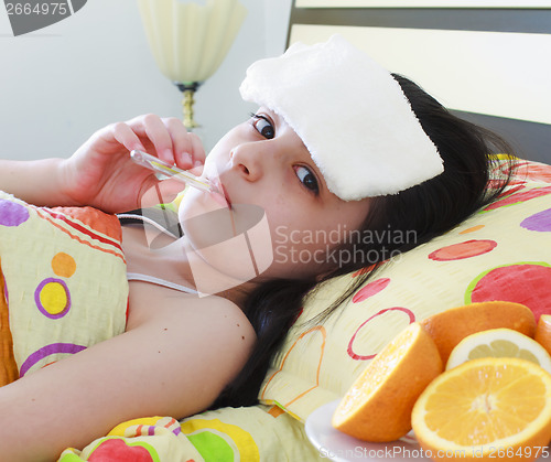 Image of Sick young girl with a thermometer in bed