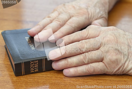 Image of old man hands on bible