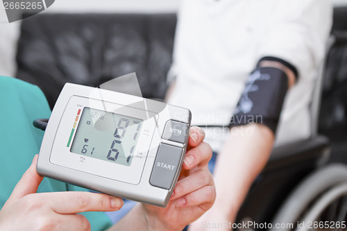 Image of Blood pressure check for young adult in wheelchair.