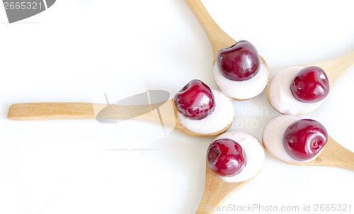 Image of Wooden spoon is with yogurt and cherries