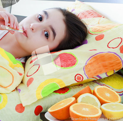 Image of Sick little girl with a thermometer in bed