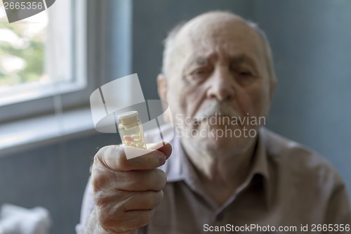 Image of old man holding pills