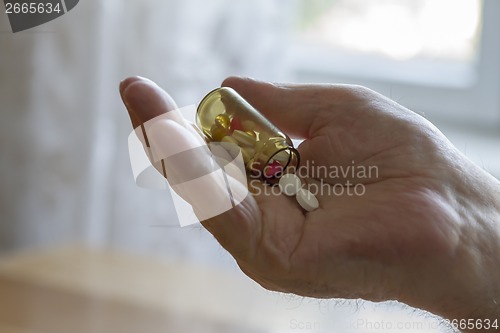 Image of old man holding pills