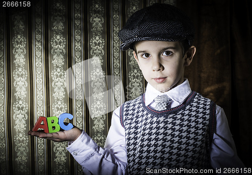 Image of Child in vintage clothes hold letters a b c