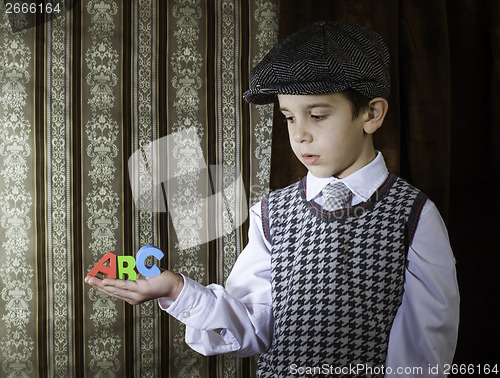 Image of Child in vintage clothes hold letters a b c