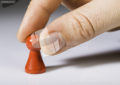 Image of Hand holding red pawn on white background