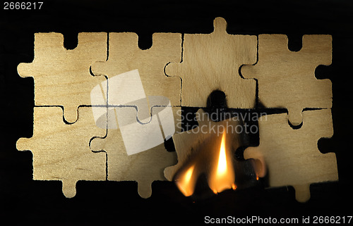 Image of Burning wooden puzzle on dark background.