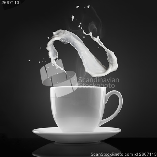 Image of white cup with hot liquid and milk splash on black