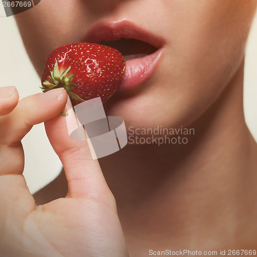 Image of Young woman biting strawberry isolated on white