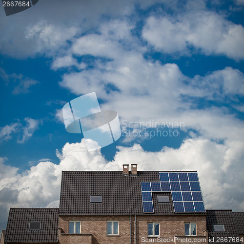 Image of New houses with solar panels on roof under blue sky and clouds