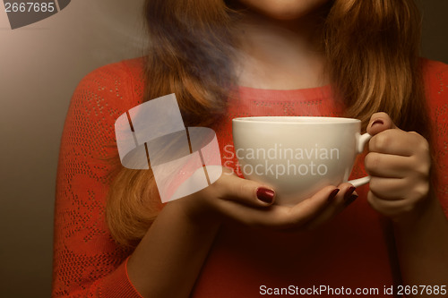 Image of woman holding hot cup and smiles