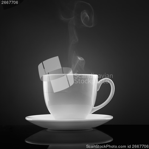 Image of white cup with hot liquid and steam on black