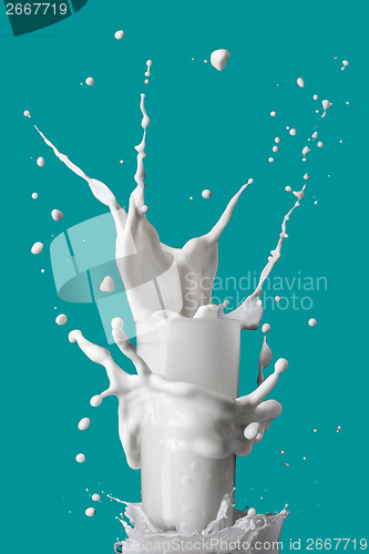 Image of milk splash in glass isolated on blue background