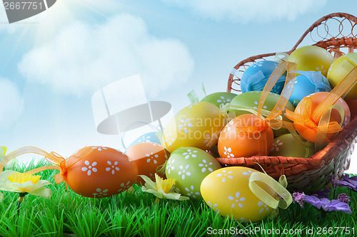 Image of color easter eggs in basket against blue sky and clouds