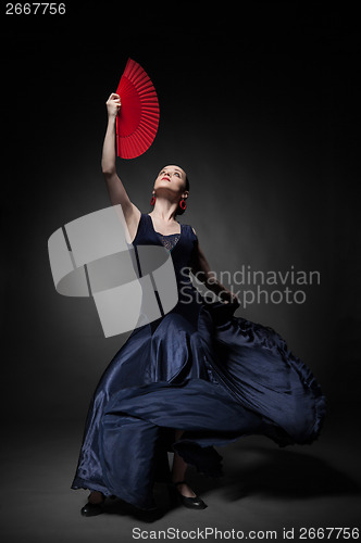 Image of young woman dancing flamenco on black