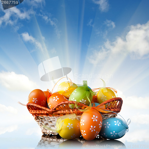 Image of color easter eggs in basket against blue sky and clouds