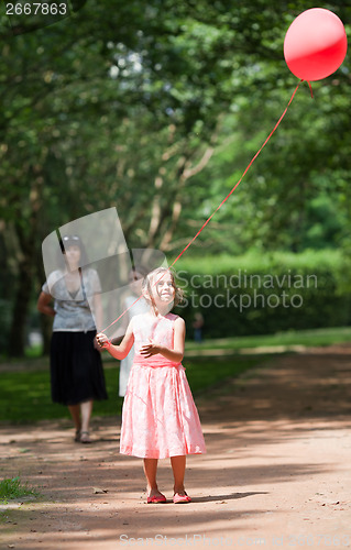 Image of Little girl looks up at balloon held aloft