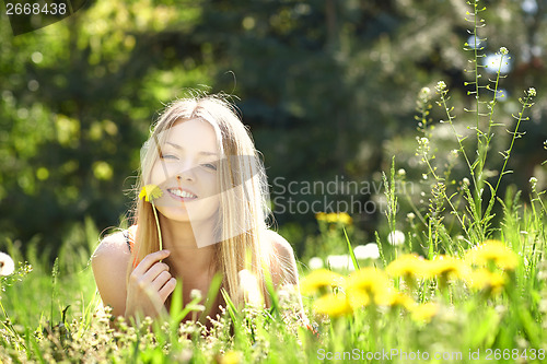 Image of Spring girl lying on the field of dandelions