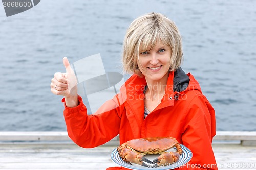 Image of Happy woman holding cooked crab on white plate