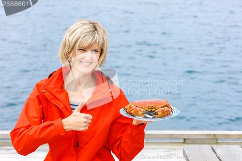 Image of Happy woman holding cooked crab on white plate