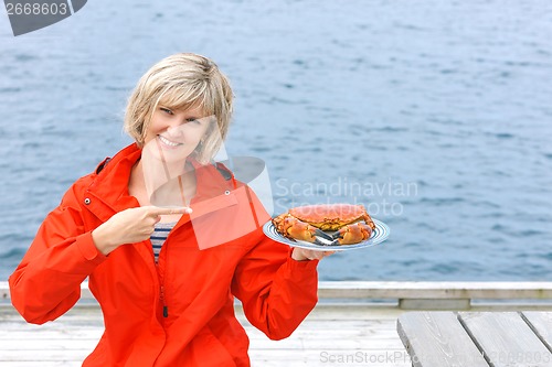 Image of Happy woman holding cooked crab on white plate