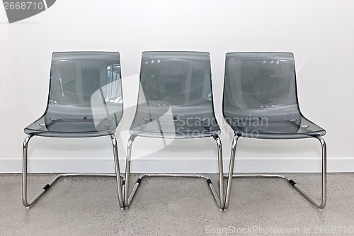 Image of Three plastic chairs against wall