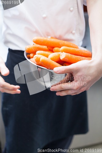 Image of Chef in uniform preparing fresh carrot batons