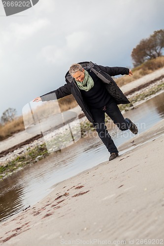 Image of Happy senior woman frolicking on the beach