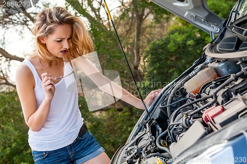 Image of Woman inspecting her car engine after a breakdown