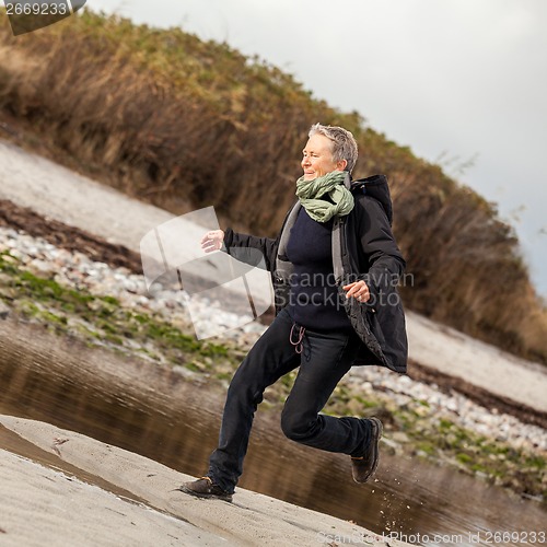 Image of Happy senior woman frolicking on the beach