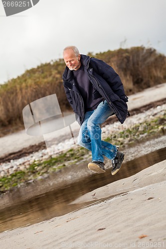 Image of Elderly energetic man running along a beach