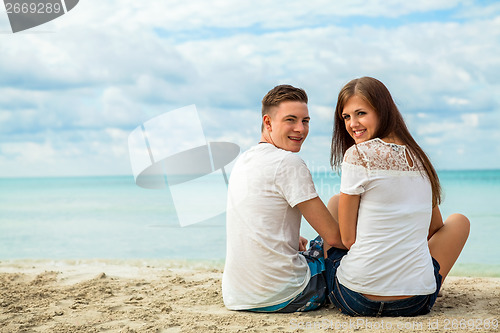 Image of romantic young couple sitting on the beach in summer