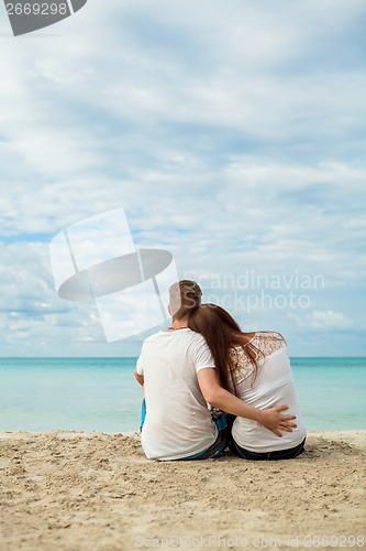 Image of romantic young couple sitting on the beach in summer