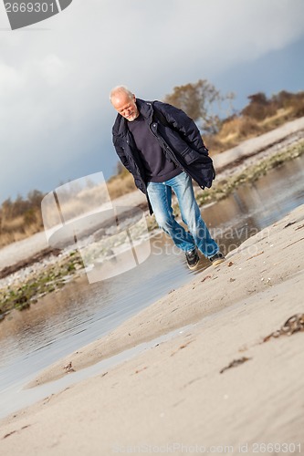 Image of Elderly energetic man running along a beach