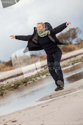 Image of Happy senior woman frolicking on the beach